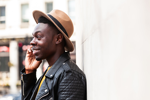 Happy black man talking on the phone and smiling - Fashion young man in London enjoying a phone conversation - Lifestyle, technology and communication concepts