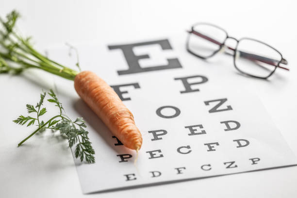 istock Fresh carrots as a source of vitamin A placed on the eye test chart. Glasses and carrot, concept of good eyesight. 1987695115