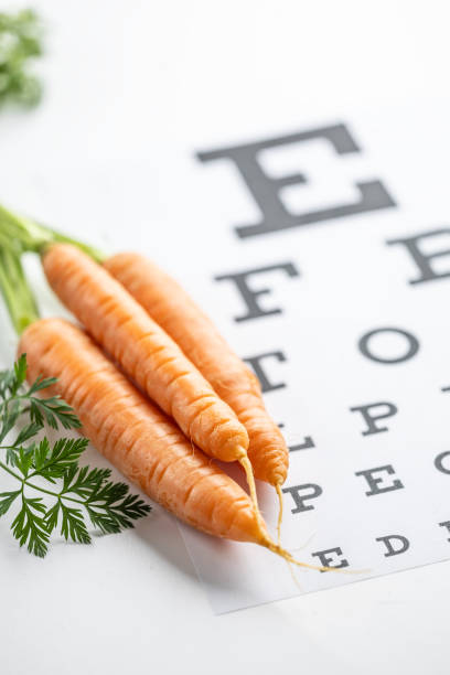 istock Fresh carrots as a source of vitamin A placed on the eye test chart. 1987695132