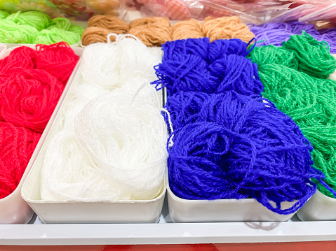 Close-up photo of colorful cotton thread yarn on display rack shelf in a store. Plant hemp linen rope wool spool. Concept for traditional handmade textile, small industry, old fashioned, vintage.