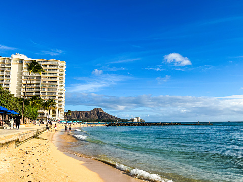 A peaceful Waikiki beach in Honolulu on Oahu Island on Hawaii. Deep blue sky and tall palm trees make it a perfect vacation destination