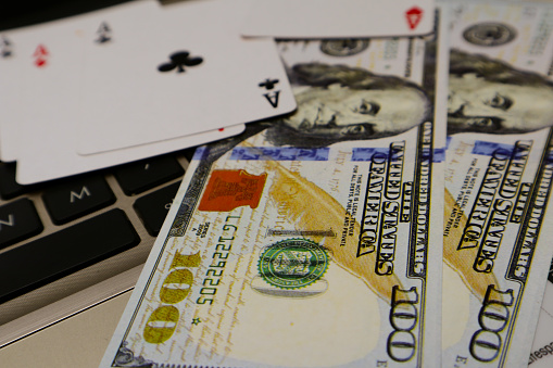 hundred dollar bills and poker cards over keyboard background. online gambling concept