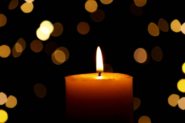 istock Candle burns Isolated On Black background with Christmas Lights Defocused Bokeh. 1987730040