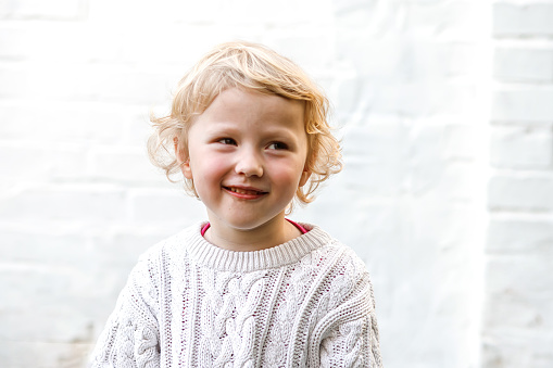 Little cute girl in a warm white sweater smiling. Portrait of a 4-year-old girl