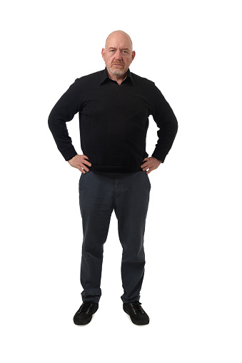 front view of a serious man looking at camera and arms akimbo on white background