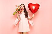 Woman hold bouquet of flowers and heart-shaped balloon