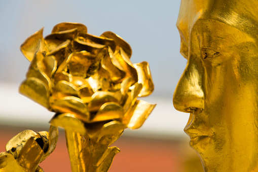 Golden flower adorning a majestic statue featuring a man's visage