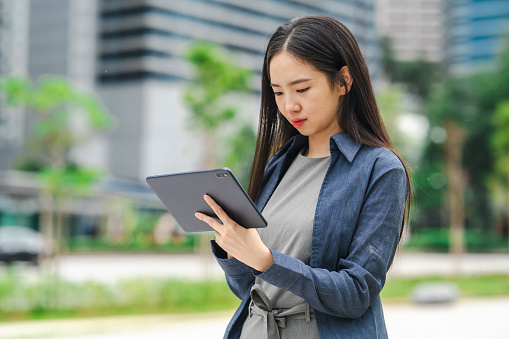 Young Asian woman using digital tablet in urban city. Lifestyle outdoor activity concept.