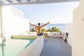 Seaside Stretch: Young Man's Tranquil Moment by the Pool with Arms Outstretched, Embracing the Sea View