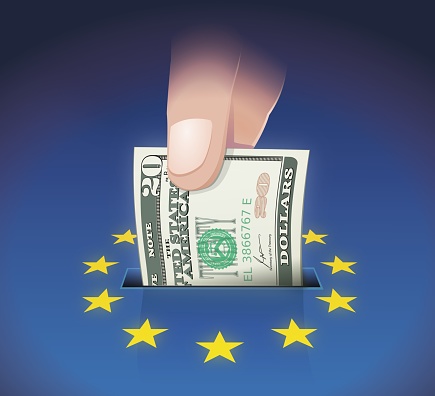 A hand places an American 20 dollar bill in a slot on a background in the colors of the European Union flag