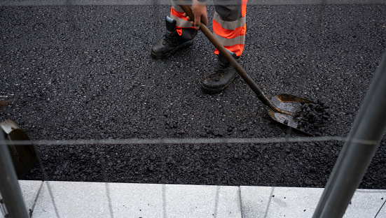 Worker levelling fresh asphalt on a road construction