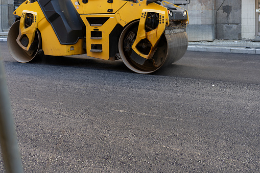 A big vibration  roller compacting asphalt on a new road