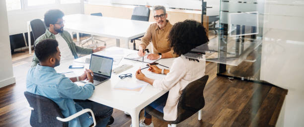 istock In a wide office shot, four professionals are deep in discussion around a table 1987788743