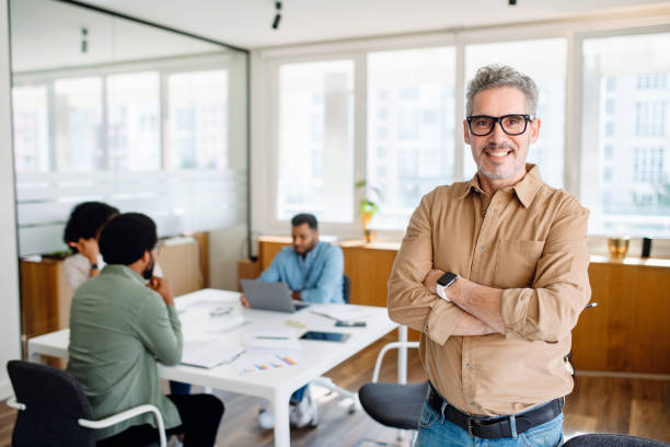 istock A senior professional with arms folded stands confidently in a bright office 1987788748