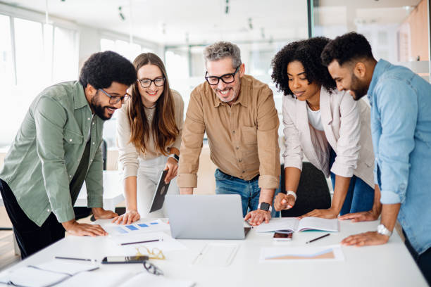 istock Diverse colleagues gather around a laptop with bright expressions 1987788769