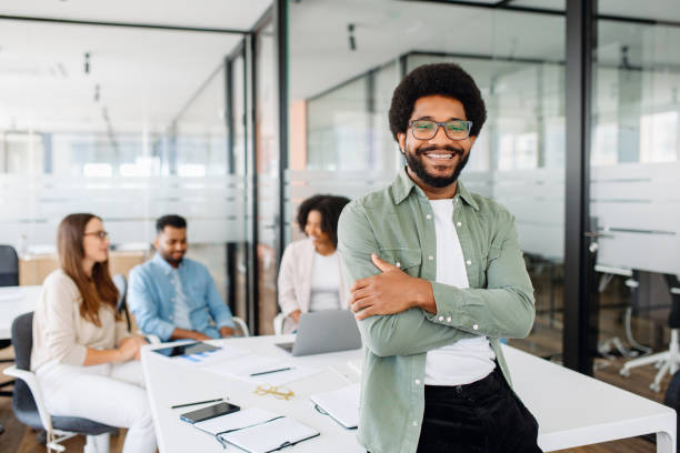 istock Young man stands with arms crossed in modern office space 1987788777