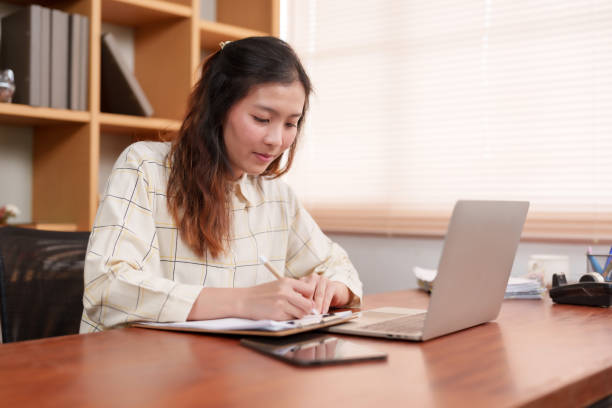 istock Diligent Asian businesswoman writes notes, her focused attention reflecting dedication to her work. professional pensively jots down ideas, concentration evident amidst day of productive office work 1987791990