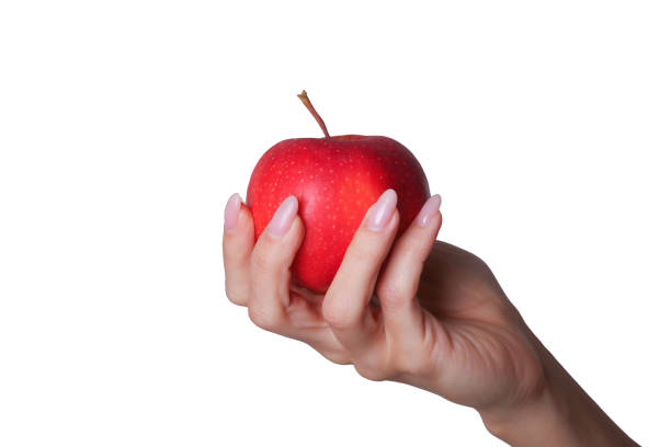 istock Woman's hand gripping a red apple on a clean white backdrop. 1987806979