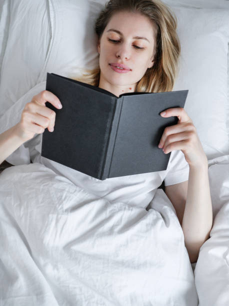 istock Young pretty girl reading a book in bed before going to sleep 1987816995