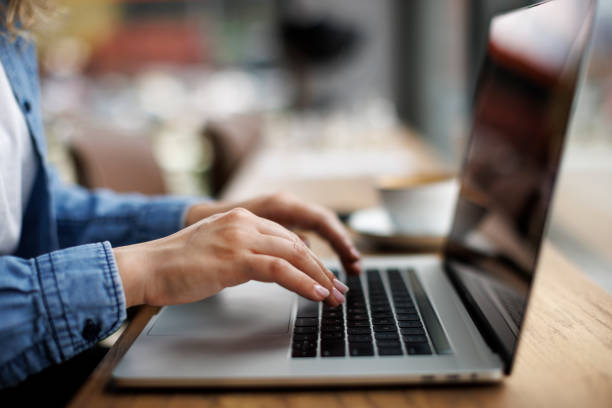 istock Close-up hands of woman while working, using laptop computer and drink coffee at a cafe 1987830381