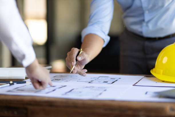istock Brainstorming group of architects and engineers discuss building blueprint design and construction project planning on wooden table in office. 1987834159