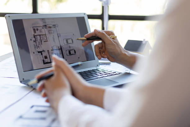 istock Brainstorming group of architects and engineers discuss building blueprint design on laptop and construction project planning on wooden table in office. 1987834168