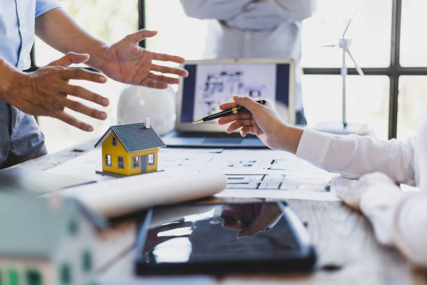 istock Brainstorming group of architects and engineers discuss building blueprint design and construction project planning on wooden table in office. 1987834718
