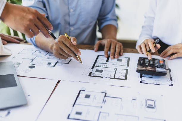istock Brainstorming group of architects and engineers discuss building blueprint design and construction project planning on wooden table in office. 1987835260