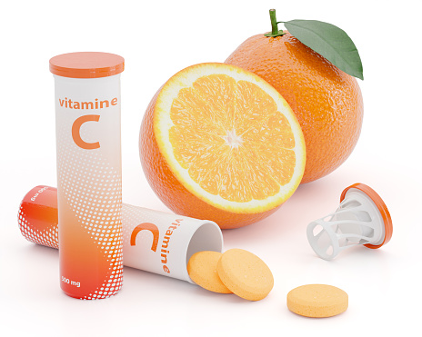 Effervescent Vitamin C tablets spilling out of plastic tube with juicy orange fruit isolated on white background. 3D render for vitamin and mineral supplements concept.