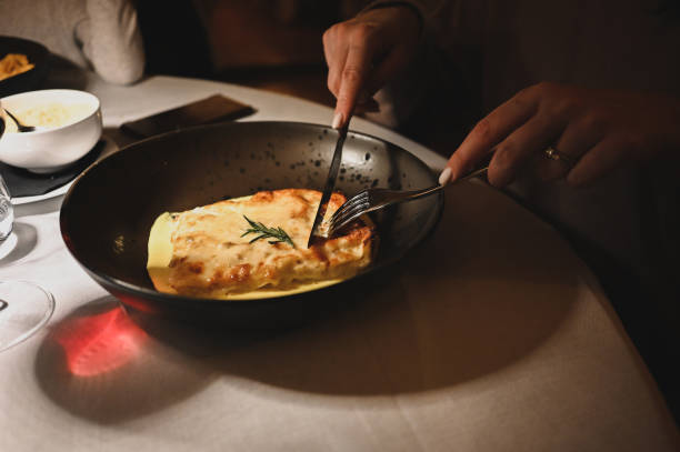 zbliżenie na dłonie kobiety jedzącej smaczną lasagne w luksusowej restauracji. - chloroplasty zdjęcia i obrazy z banku zdjęć