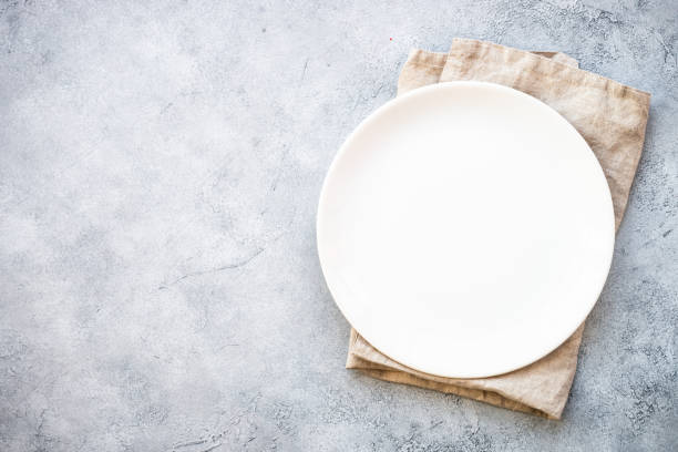 istock White plate and napkin at stone table. 1987873867