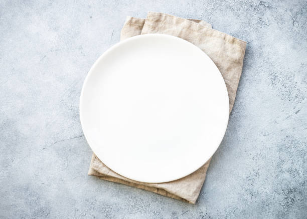 istock White plate and napkin at stone table. 1987873870