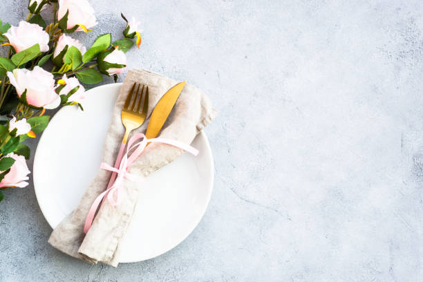 istock Table setting, festive table serving with white plate, modern cutlery and pink flowers. 1987874392