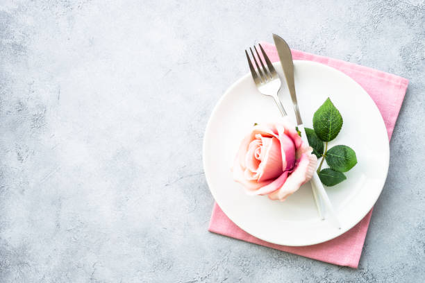 istock Spring Table setting with white plate and rose flowers. Top view. 1987880236