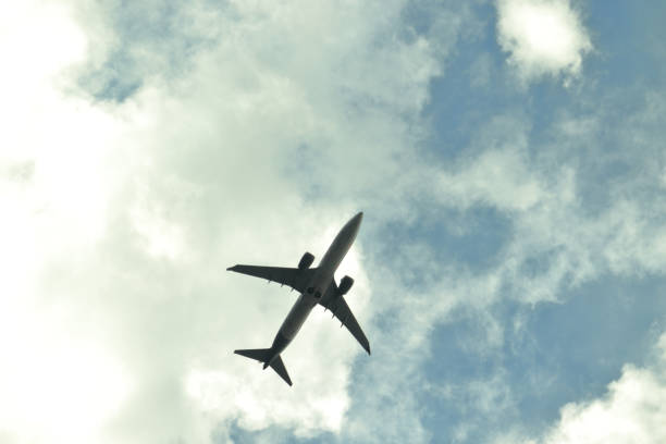 semi silhouette of jet plane flying under a blue sky covered by white clouds - POA,  SAO PAULO,  BRAZIL.