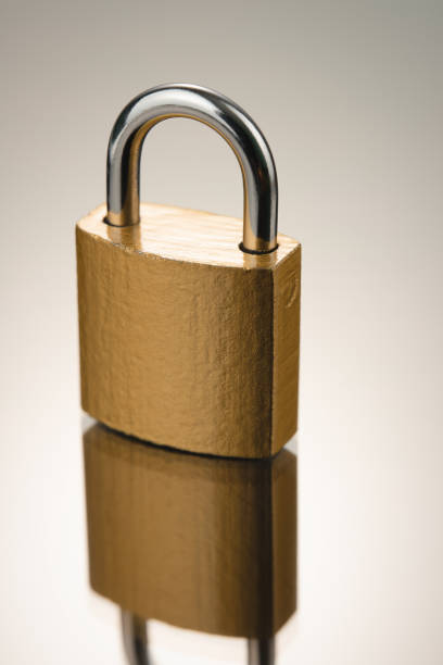 istock Closed metal padlock in golden color on reflective surface. Vertical frame. 1987893537