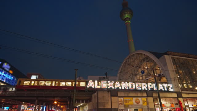 Slow motion Moving train at Alexanderplatz a large public square and transport hub at night in the central Mitte district of Berlin, Germany