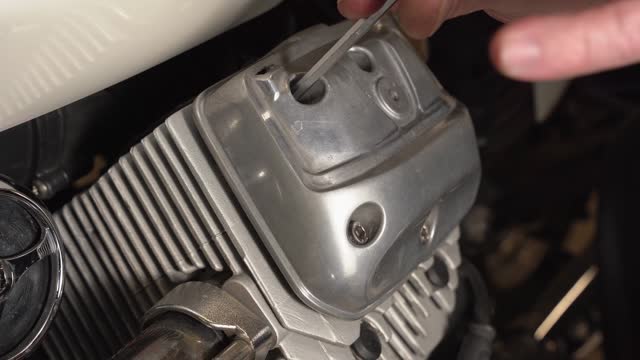 The mechanic installs and screws the valve cover