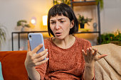 Upset displeased woman using smartphone surprised by lottery results or bad news loses fail game