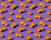 Isometric pattern with orange pumpkins on purple background