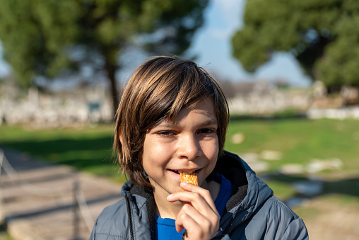 little boy eats crackers in the park