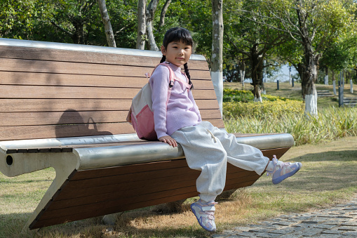Little girl sitting on bench looking at camera