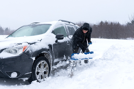 A young man shoveling snow in a driveway during a blizzard.