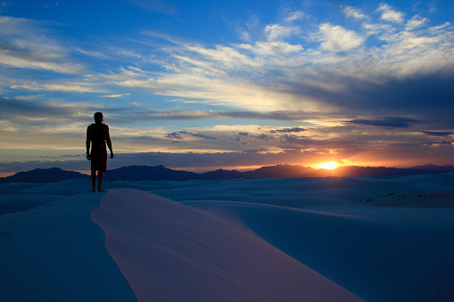 Man sitting on rock on desert and watching sunset