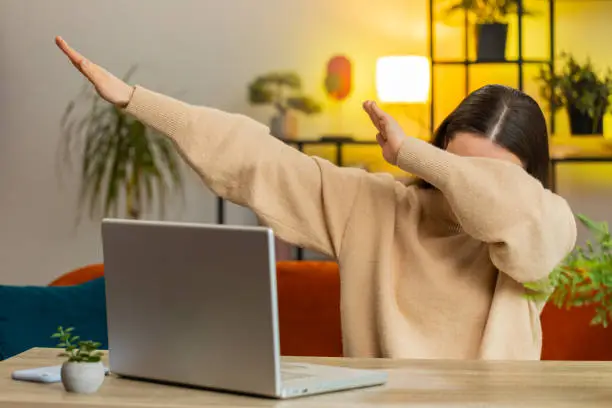 Photo of Happy Caucasian woman having fun dancing dabbing raising hands making dub dance gesture at home room