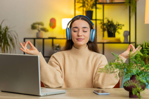 jolie femme écoutant de la musique, respire profondément méditant avec des pensées concentrées paisibles à la maison - lotus position audio photos et images de collection