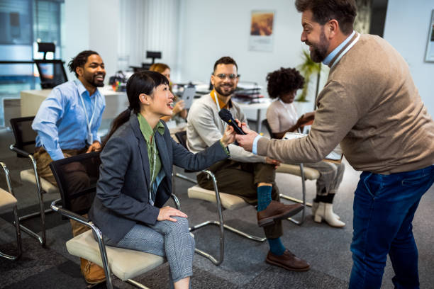istock Bussines man lecturing his multiethnic colleagues. Having a speach while holding a microphone. 1987971051