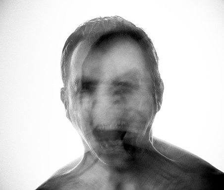 Unfocused man showing anger. It is a scaring monochrome image which could be use for carnival or halloween. White background. Mental disorders concept.