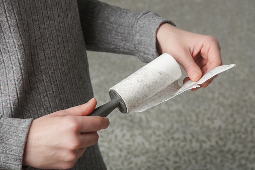 Hair remover roller. Woman using reusable clothes lint roller cleaner.