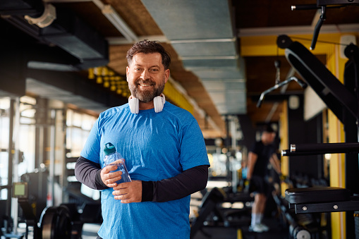 Happy mature man having sports training in a gym and looking at camera. Copy space.